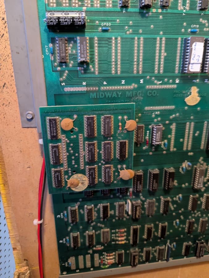 Close-up of an arcade circuit board during a board-level repair