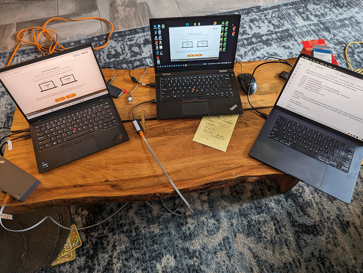 Three laptops set up side by side for data transfer and setup